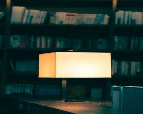 A warm desk lamp illuminating a book on a table in the evening