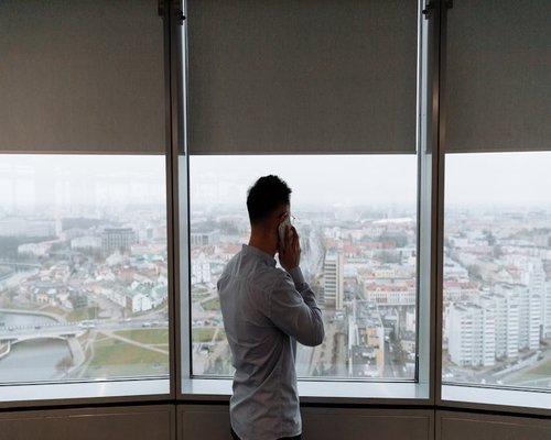 Man taking a short break looking out the window of a high-rise building